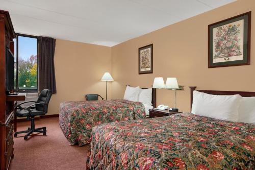 a hotel room with two beds and a desk and a chair at Days Inn by Wyndham Hagerstown I-70 in Hagerstown