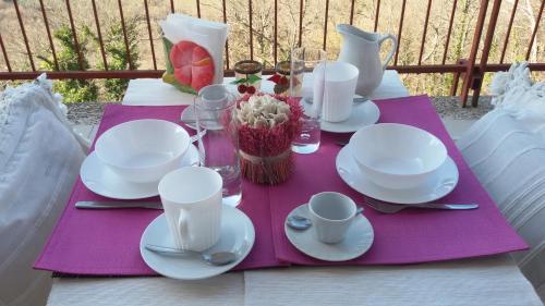 a table with white plates and cups on a purple napkin at Belvedere del Lago in Montefiascone