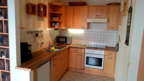 a kitchen with wooden cabinets and a sink and a microwave at Ferienapartment Sonnensegler Insel Usedom in Karlshagen