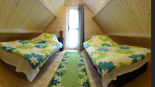 JezierzanyにあるDomki Letniskowe U Cichegoのベッド2台が備わるグリーンカーペットフロアの客室です。