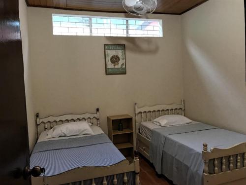 two beds in a room with a window at Hostal Augustos in San Juan del Sur