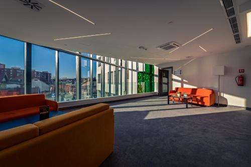 a living room with orange furniture and large windows at Hotel Garden Hill in Velika Gorica