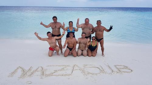 a group of people posing for a picture on the beach at Liberty Guesthouse Maldives in Mahibadhoo