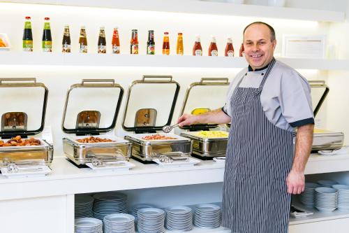 a chef standing in front of a counter with food at ASTORIA Hotel & Medical Spa in Karlovy Vary