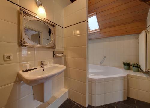 a bathroom with a sink and a tub and a mirror at Hotel Restaurant De Keurvorst in Ravenstein