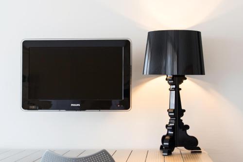 a black lamp with a television on a wall at B's Strandappartementen in Domburg