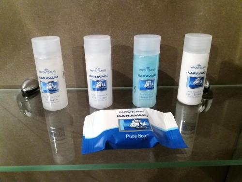 a glass shelf with four bottles of sunscreen on it at Vytina Mountain View Hotel in Vytina