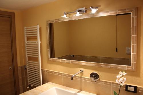 La salle de bains est pourvue d'un grand miroir au-dessus d'un lavabo. dans l'établissement Le Maioliche Junior Suite, à Agrigente
