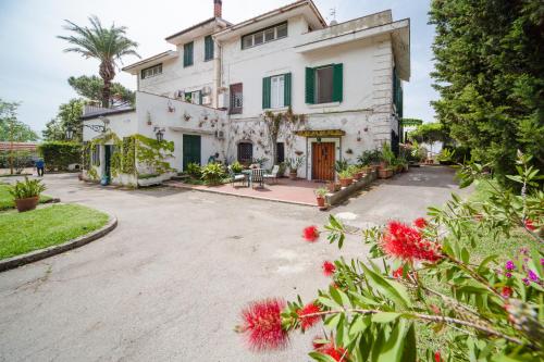 une grande maison blanche avec des fleurs rouges devant elle dans l'établissement B&B Casina de Goyzueta, à Torre del Greco