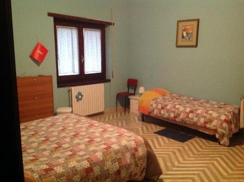 a bedroom with two beds and a dresser and a window at Bed & Breakfast da Charlie in LʼAquila