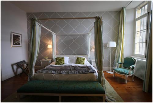 ein Schlafzimmer mit einem Himmelbett und einem Stuhl in der Unterkunft Château de Courtebotte in Saint-Jean-de-Blaignac