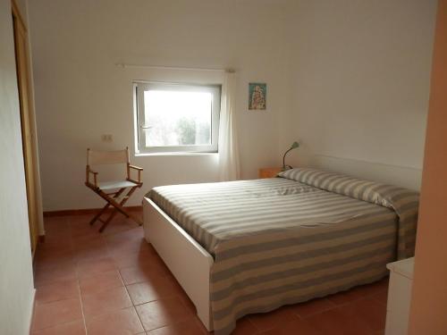 a bedroom with a bed and a chair and a window at Dèpendance Argentario in Porto Santo Stefano