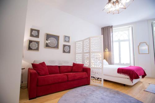 a living room with a red couch and a bed at Almada Story Apartments by Porto City Hosts in Porto