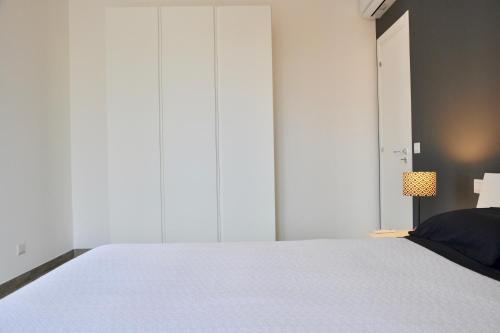 a bedroom with a large white bed and a lamp at Donnalucata Ospitalità Diffusa in Donnalucata