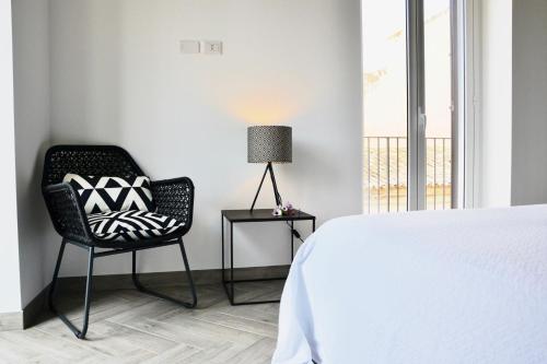 a bedroom with a bed and a chair and a lamp at Donnalucata Ospitalità Diffusa in Donnalucata