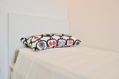 a bed with a black and white pillow on it at Donnalucata Ospitalità Diffusa in Donnalucata