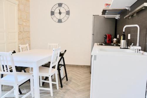 a kitchen with a white table and chairs and a clock at Donnalucata Ospitalità Diffusa in Donnalucata