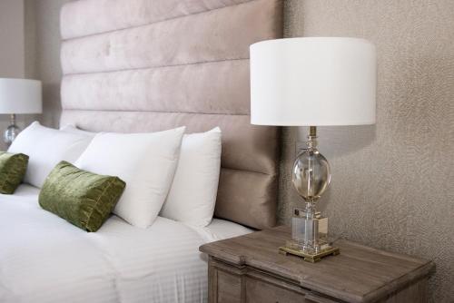 a lamp on a night stand next to a bed at Roundthorn Country House & Luxury Apartments in Penrith
