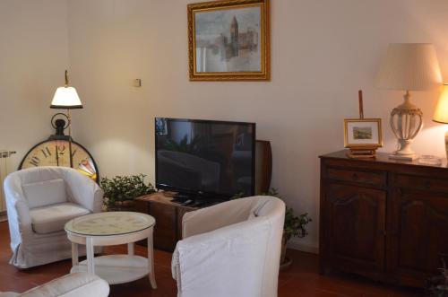 a living room with a tv and two chairs and a table at Villa Schiatti in Cortona