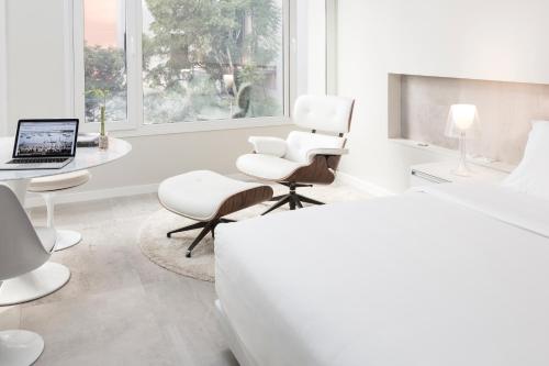 亚松森Hub Hotel Asuncion的白色卧室配有床、书桌和椅子