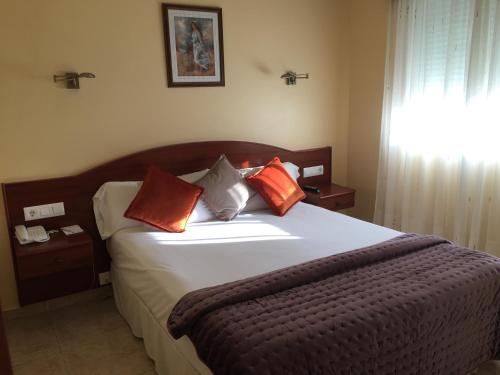 a bedroom with a bed with orange pillows on it at Hotel & Apartamentos Cons da Garda in San Vicente de O Grove
