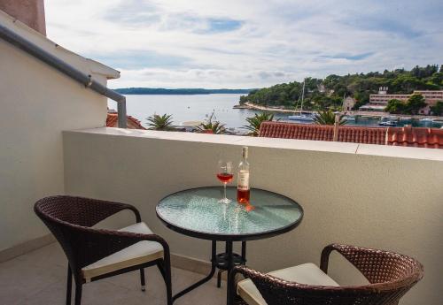 a glass table with two glasses of wine on a balcony at DeVecchi rooms in Hvar