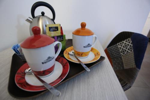 two tea cups and a tea kettle on a tray at Hotel Eubea in Reggio Calabria