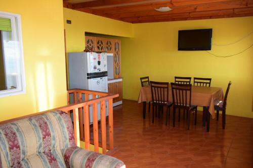 cocina y comedor con mesa y TV en Cabañas Urra House, en Viña del Mar