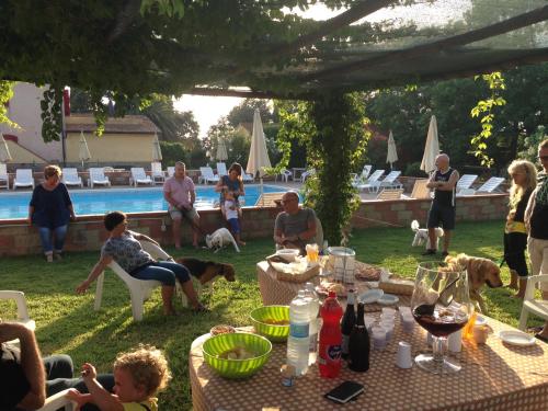 un grupo de personas sentadas alrededor de una mesa cerca de una piscina en Casa Vacanze Guardamare, en San Vincenzo