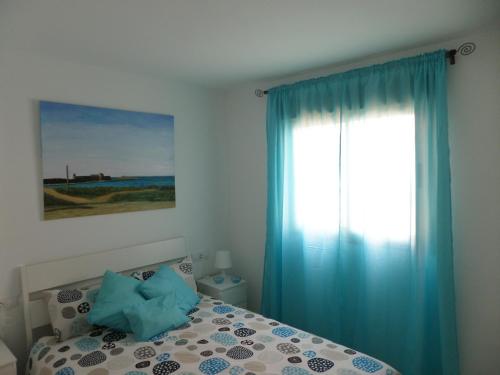 プエルト・デル・ロサリオにあるApartamento Puertoのベッドルーム1室(ベッド1台、青いカーテン付きの窓付)
