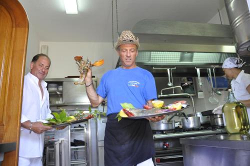 a man in a kitchen holding a tray of food at Hotel Casa Giuseppina in Ischia