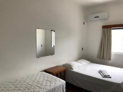 a room with two beds and a mirror and a window at Central Plaza Hotel Tupa in Tupã