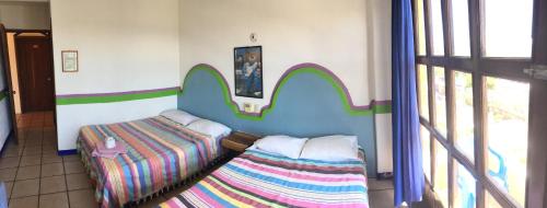 a room with two beds in a room with a window at Pargos Hotel & Cowork in Puerto Escondido