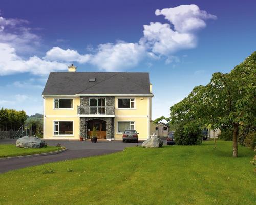 a yellow house with a car parked in the driveway at DunnCourt House in Killarney