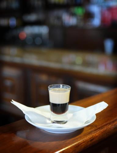 a glass of coffee on a plate on a table at Hotel Sojovalo in Kampala