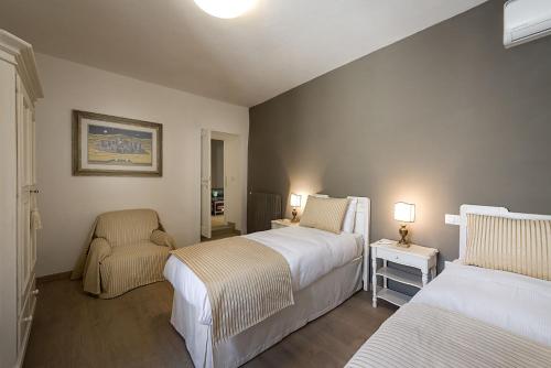 a hotel room with two beds and a chair at Villa Elisa in Spello