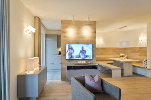 a living room with a couch and a tv on a wall at Schlosskopf Suiten in Sankt Anton am Arlberg
