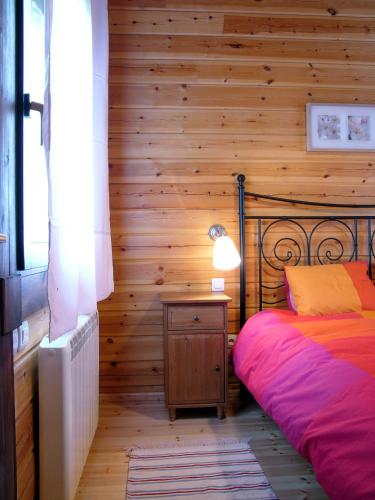 a bedroom with a bed and a wooden wall at La Albarina in Galende