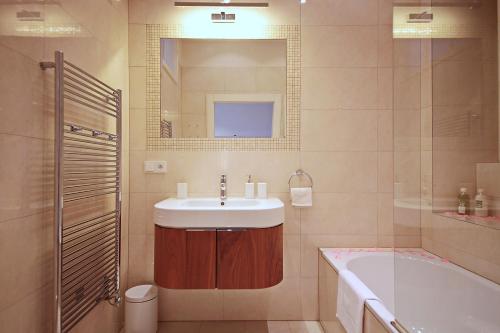 uma casa de banho com um lavatório, uma banheira e um espelho. em Apartment in the heart of Prague em Praga