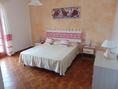 een slaapkamer met een bed en 2 tafels met lampen bij Appartamenti Budoni in Budoni