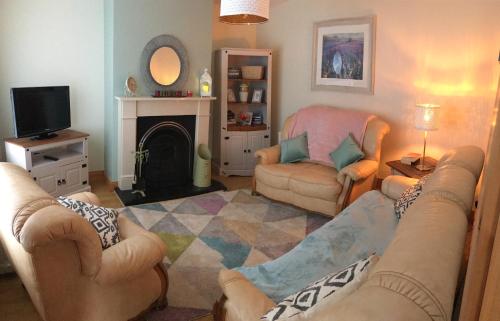 sala de estar con sofá, sillas y chimenea en No 4 Ballymastoker Cottage, en Portsalon