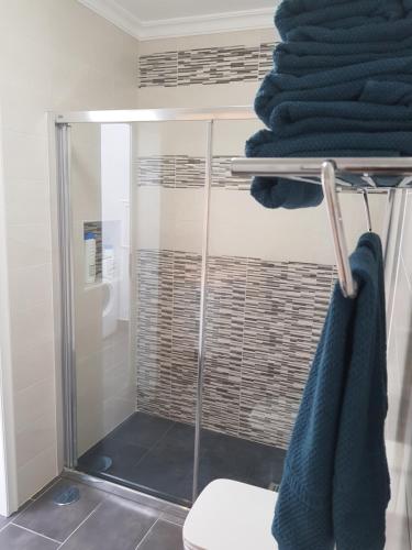 a bathroom with a shower with blue towels on a rack at Apartamentos Capellania in Puerto del Carmen