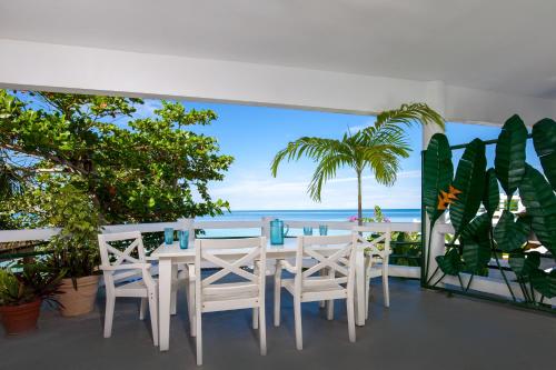 a table and chairs on a balcony with a view of the ocean at Beach House Condos, Negril in Negril