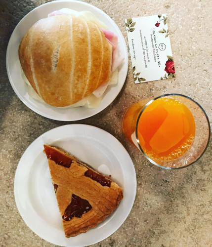two plates of food with a piece of cake and orange juice at Locanda La Posta Nöa - B&B in Vezza dʼOglio
