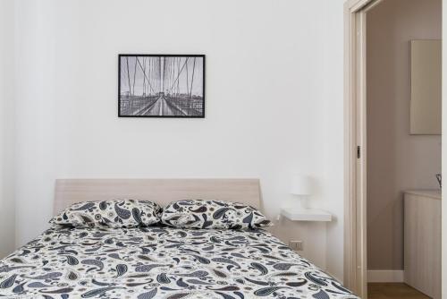 ein weißes Schlafzimmer mit einem Bett mit einem Bild an der Wand in der Unterkunft Fantoni Suite in Mailand
