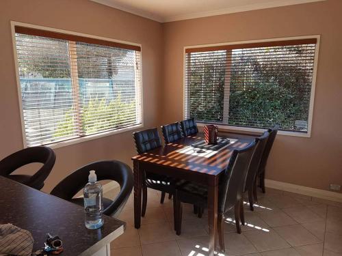 a dining room with a table and chairs and two windows at The Retreat Taupo in Taupo