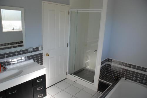 a bathroom with a shower and a sink and a mirror at The Retreat Taupo in Taupo