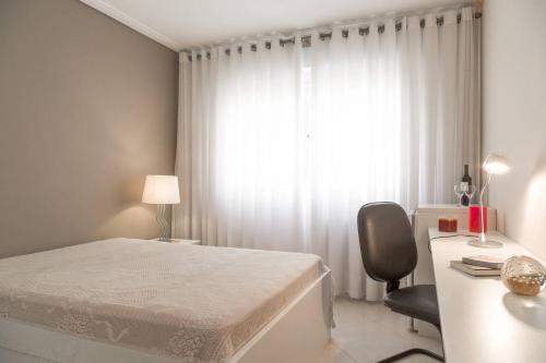 a bedroom with a bed and a desk and a window at HomeStay 2 - Avenida Carlos Gomes in Porto Alegre