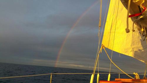 a rainbow in the sky over the ocean with a boat at Ferienwohnung Rügen-Freiheit in Putgarten