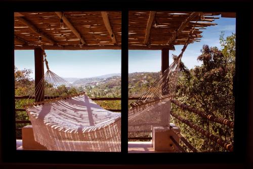 a hammock on a porch with a view of the mountains at Casa Mono in San Agustinillo